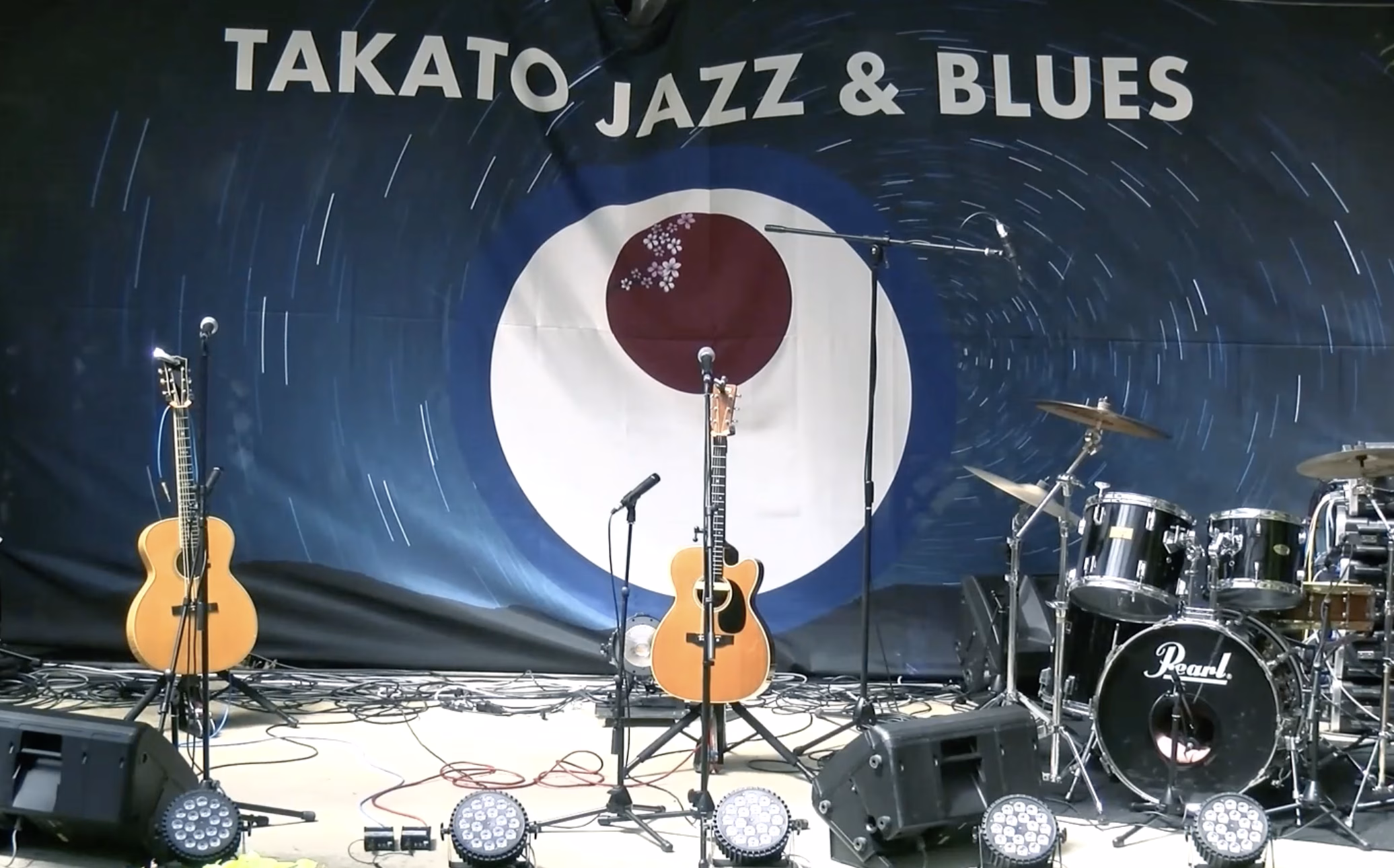 高遠ジャズ＆ブルース2025のステージ。ギター、ドラム、PA機材が並ぶライブ演奏の準備中の写真。