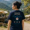 TAKATO RHYTHM Tシャツ 2026 レディース着用イメージ TAKATO RHYTHM Tシャツを着た女性の後ろ姿と高遠のフェスティバル風景